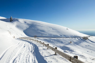 Scenic view of snow covered mountains against clear blue sky