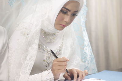 Beautiful bride writing on paper