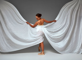 Portrait of young woman standing against curtain