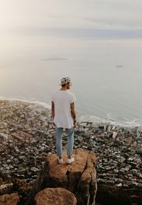 Rear view of man standing on rock by sea