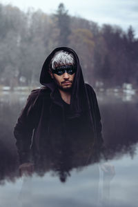 Digital composite image of man standing in lake against trees and sky