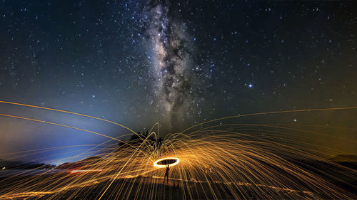 Silhouette man spinning wire wool against star field