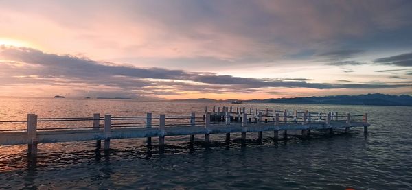 Pier over sea against sky during sunset