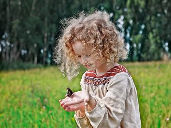 Cute girl with butterfly on hand in park