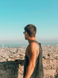 Rear view of man looking at sea against clear sky