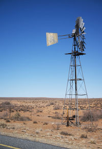 Windmill on field against clear blue sky