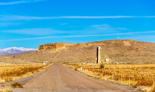 Road leading towards mountain against blue sky