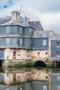 Old building by canal against sky