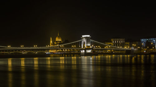 Illuminated bridge over river at night