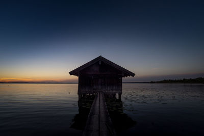 Built structure on beach against sky during sunset