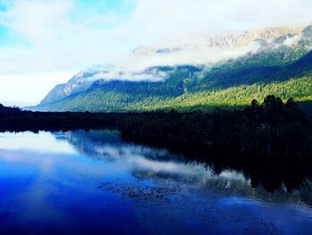 Scenic view of lake by mountains against sky