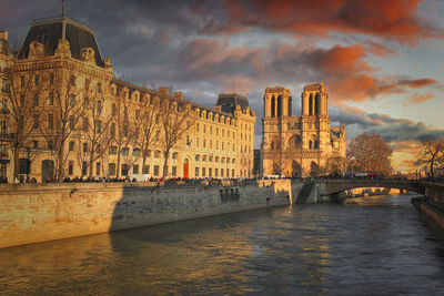 Bridge over river by buildings against sky