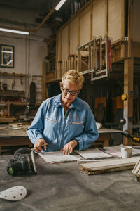 Senior craftswoman reviewing document at workshop