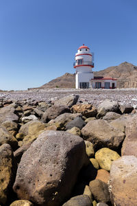 Lighthouse by sea against clear sky