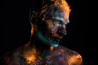 Close-up of shirtless male model with powder paint against black background