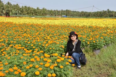 Portrait of young woman with yellow flowers in field