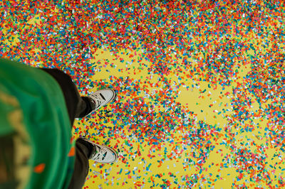 Low section of person standing on multi colored confetti