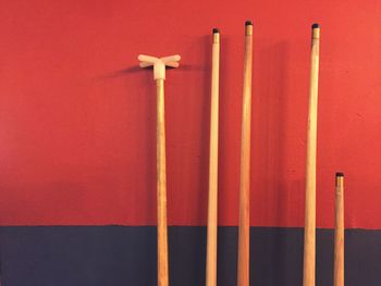 Wooden pool cues against red wall