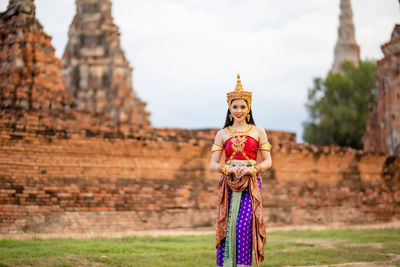 Woman in traditional clothing standing against temple