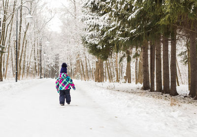 Rear view of woman walking on snow covered land