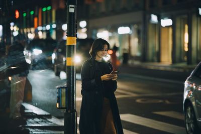 Man standing on illuminated street at night