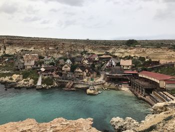 High angle view of buildings by river against cloudy sky