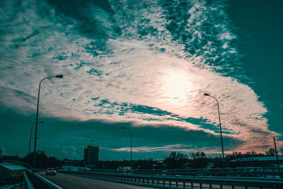 Street in city against sky during sunset