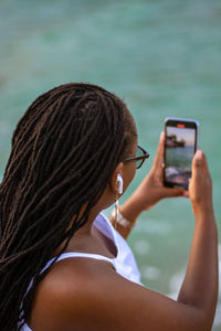 Young woman using mobile phone against sky