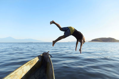 Man jumping from boat into sea