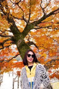 Portrait of young woman with autumn tree