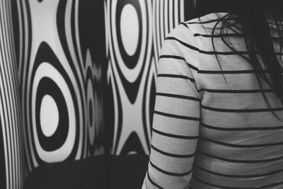 Midsection of woman standing by patterned wall