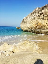 Rocks on beach against clear blue sky