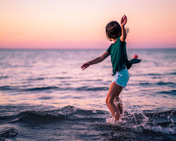 Full length of girl playing on beach during sunset