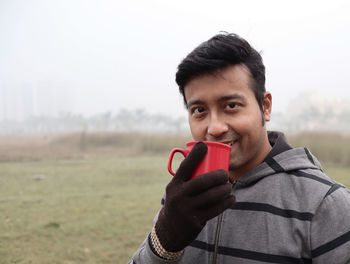 Portrait of young man using mobile phone on field