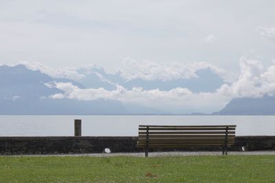 Bench on grassy field against lake