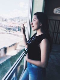 Side view of young woman looking through window