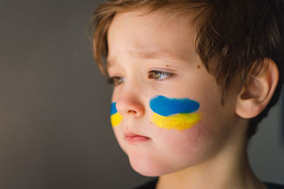 Portrait of a ukrainian boy with a face painted with the colors of the ukrainian flag.