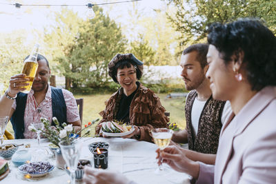 Happy friends of lgbtq community enjoying wine during dinner party in back yard