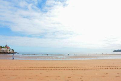 Scenic view of beach against cloudy sky