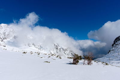 Scenic view of snow covered mountains against blue sky