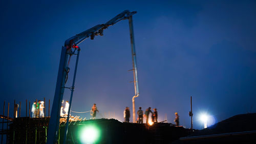 Low angle view of illuminated crane against sky at night