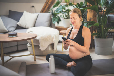 Pregnant woman using smart phone at home