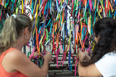 Portrait of two women placing colored ribbons on the church grid. 