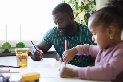Father and daughter drawing together at home