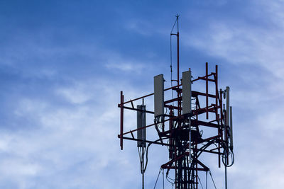 Low angle view of silhouette communications tower against sky