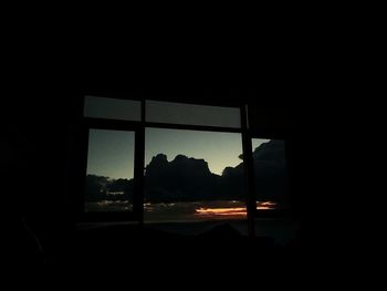 Silhouette building seen through window at sunset