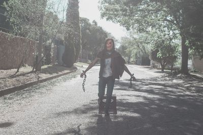 Full length portrait of young woman walking on road