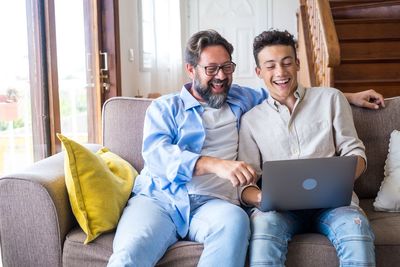 Young man using laptop while sitting on sofa at home