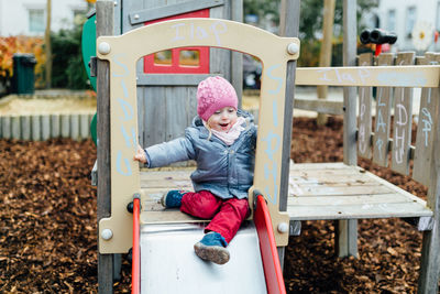 Cute girl wearing warm clothing playing at playground