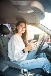 Young woman using mobile phone while sitting in car